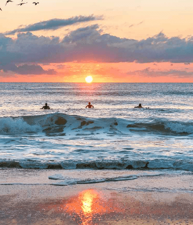 Image of Cocoa Beach pier and surfers at dawn