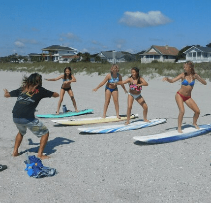 Surf instructor teaching beginner lessons on Cocoa Beach with waves in the background