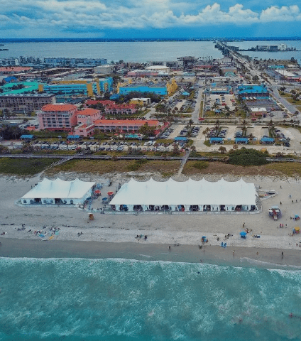 Aerial view of Melbourne Beach, Florida showing oceanfront hotels, white beach tents, and coastal buildings along the shoreline