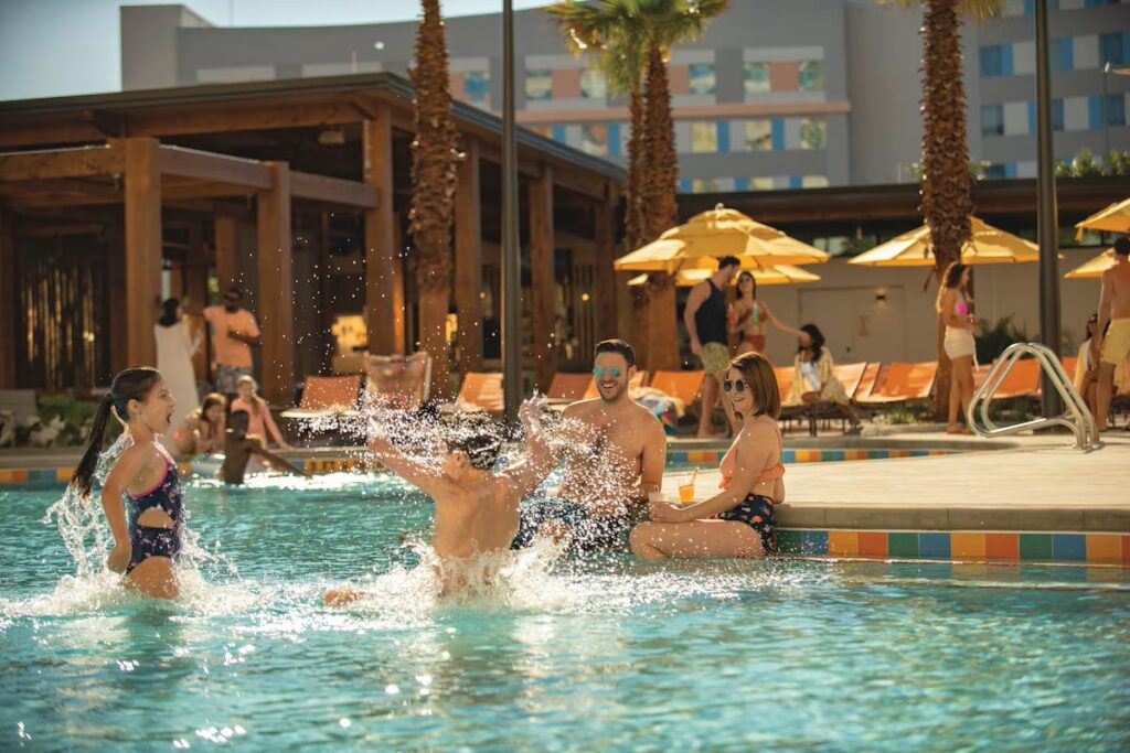 Guests enjoying the outdoor pool at Endless Summer Resort, featuring vibrant poolside activities and tropical landscaping.