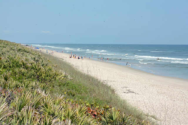 Beautiful sandy beach at Cape Canaveral National Seashore with visitors enjoying the sun and surf.