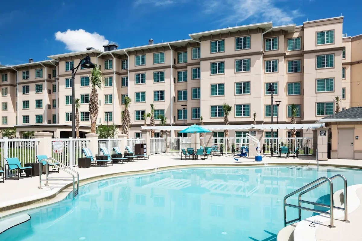 Pool area at Residence Inn by Marriott near Universal Studios in Orlando, showcasing sunny poolside lounging areas and palm trees.