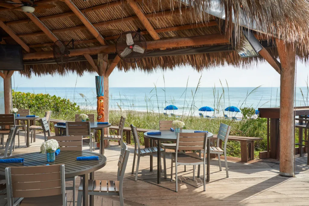 Outdoor dining area with thatched roof overlooking the beach at Crowne Plaza Hotel, Melbourne Beach, Florida.