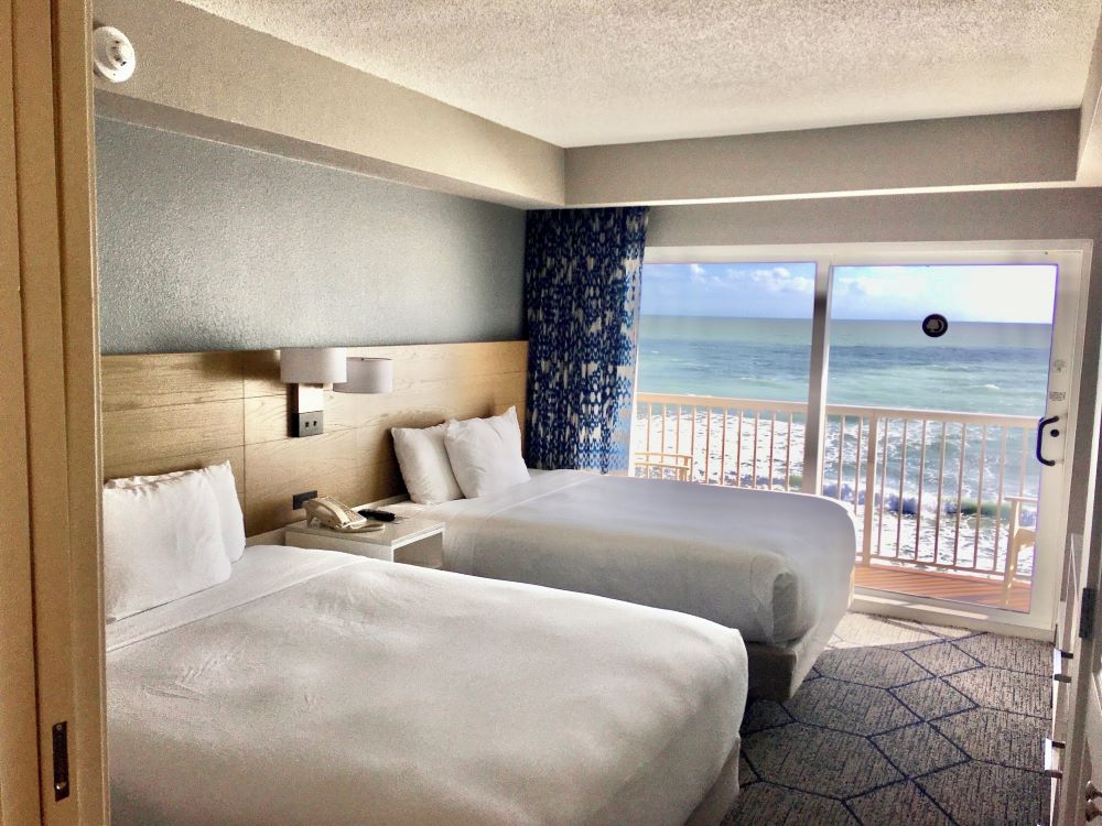 Modern guest room with two queen beds and large windows showcasing ocean views at DoubleTree Suites by Hilton Melbourne Oceanfront.