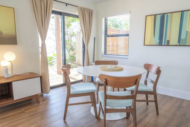 Interior of a unit at Melbourne Beach Resort featuring a modern dining table with wooden chairs, large windows, and a view of the outdoor area.