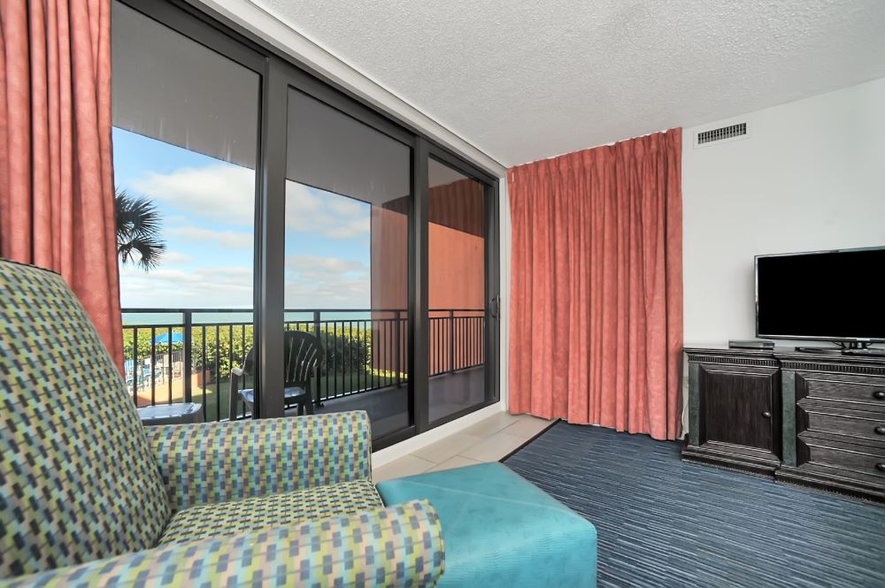 Bright and spacious guest room at Oceanique Resort with modern decor and a balcony view.