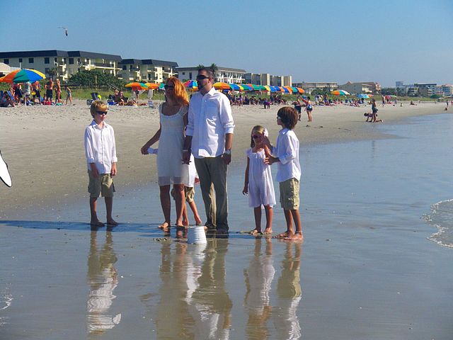 A family walking along the shoreline at Cocoa Beach, enjoying the sunny weather and ocean views.
