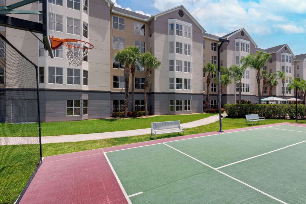 Exterior view of Homewood Suites by Hilton near Universal Studios Orlando with front entrance and palm trees Caption: Homewood Suites offers a homestyle experience with