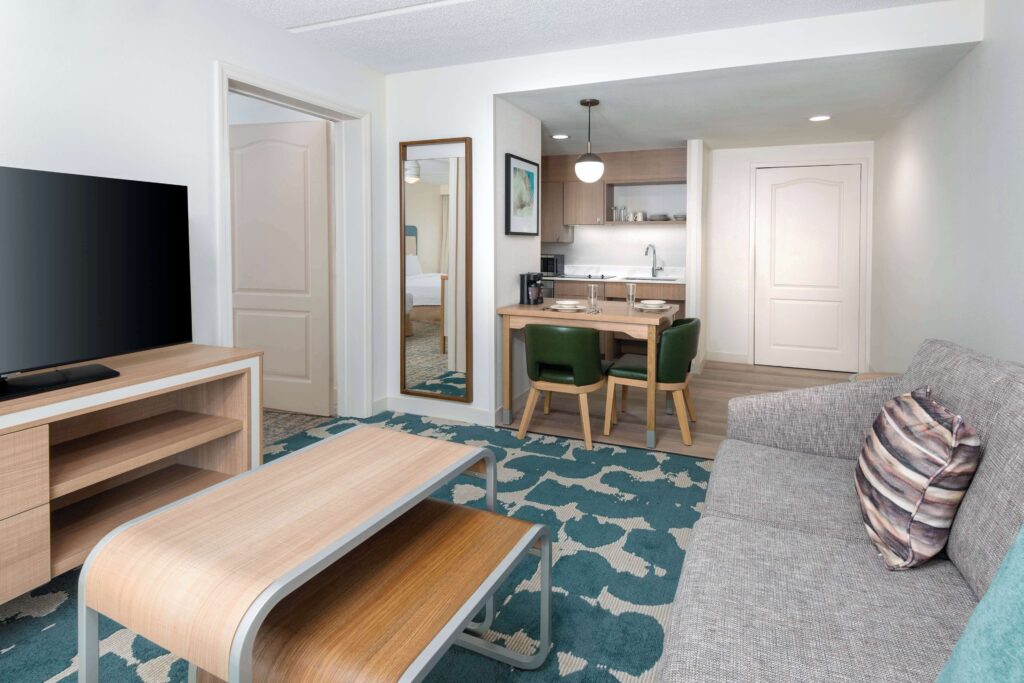 Interior of a suite at Homewood Suites with full kitchen, sofa seating, dining table, and flat-screen TV