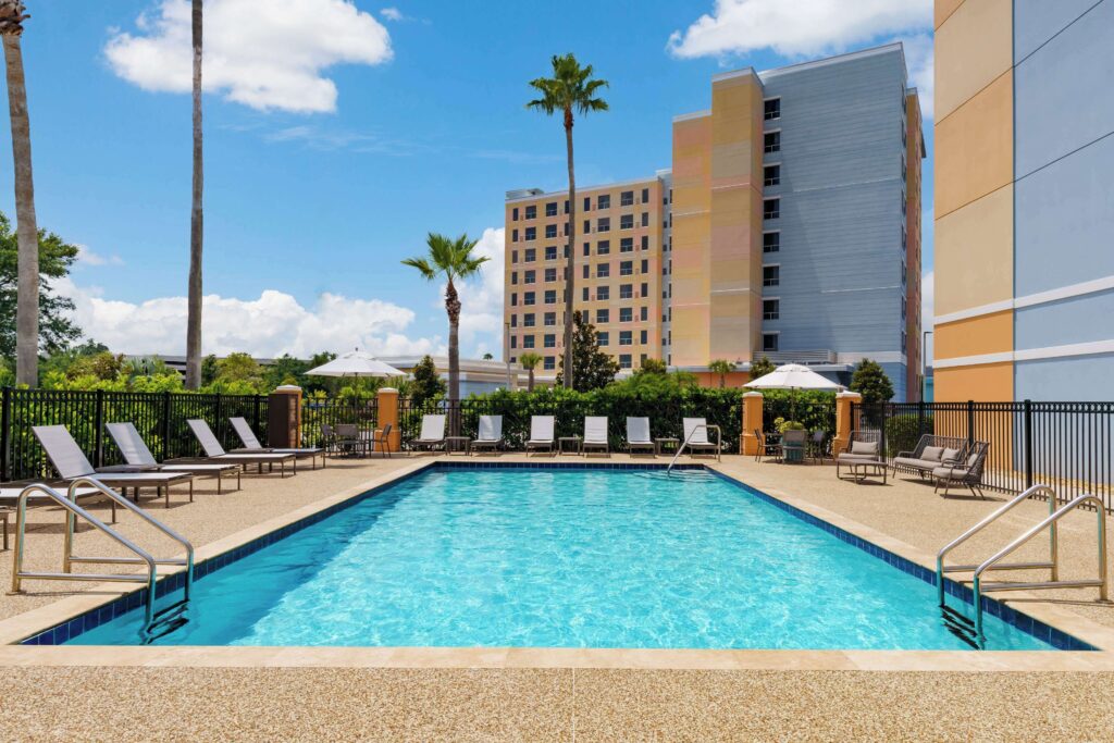 Exterior of Hyatt Place hotel across from Universal Orlando with entrance and palm trees under sunny skies