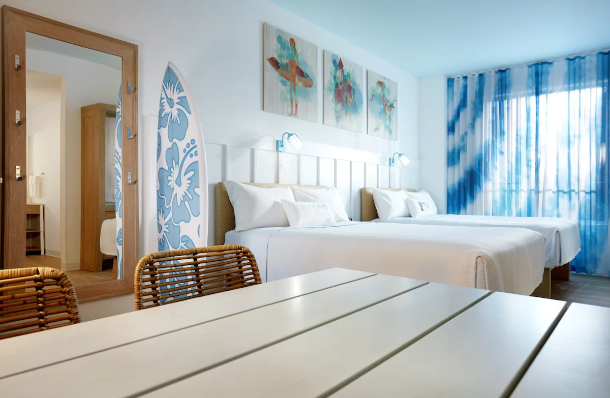 Bright surf-themed guest room at Universal’s Endless Summer Surfside Inn & Suites with two queen beds, colorful beach decor, and modern amenities