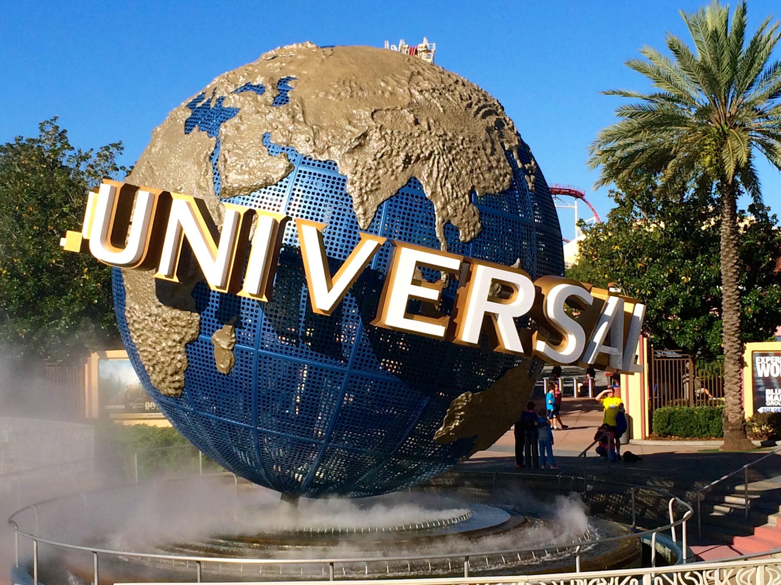 Universal Studios Orlando entrance globe with surrounding palm trees and park visitors